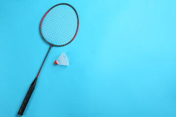 Racket and shuttlecock on light blue background, flat lay with space for text. Badminton equipment