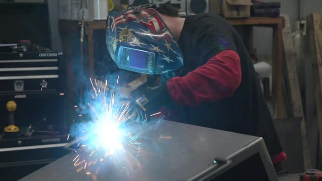 Man welding in an American Flag Helmet in a factory