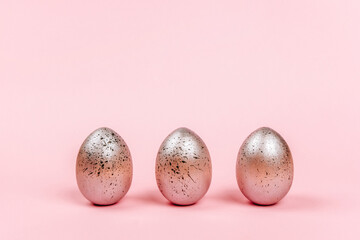 Easter eggs of silver colors with black dots on a pink background