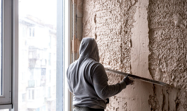 Machine Plaster. Walls With Gypsum Plaster Or Cement Plaster. Plasterer Operating Man Sprayer Equipment Machine. Construction Worker Puts A Finishing Touch On The Wall.