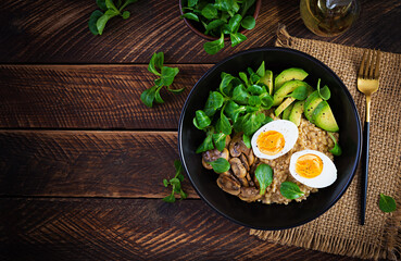Breakfast oatmeal porridge with boiled egg, avocado and fried mushrooms. Healthy balanced food. Top view, above, copy space