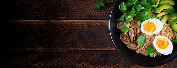 Breakfast oatmeal porridge with boiled egg, avocado and fried mushrooms. Healthy balanced food. Top view, banner, copy space