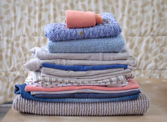Stack of folded pastel colors clothes on blurred background.
