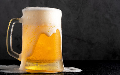 Cold beer with foam on black backgound