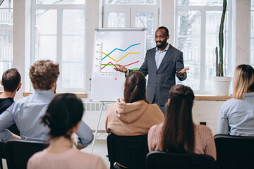 Explaining. Male speaker giving presentation in hall at university workshop. Audience or conference hall. Rear view of unrecognized participants. Scientific, business event, training. Education