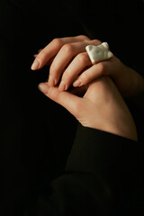 Graceful female hands with a nude manicure and a large ring in the form of a female body