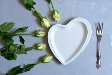 empty white plate with hearts on Ultimate Gray background with white roses and fork. The moment of a wedding, anniversary, engagement, or Valentine's Day. Happy day.