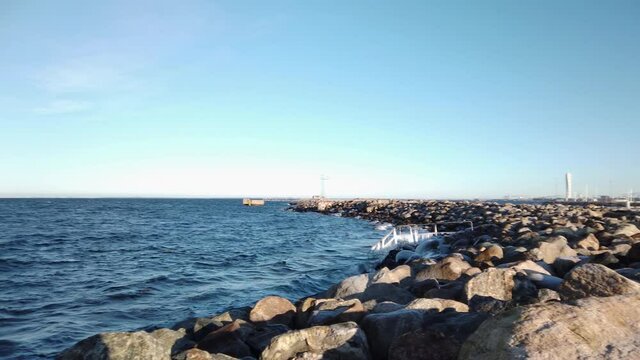 4K Pan over Oresund, Malmo, Sweden. Rocks on shore, frozen icy pier, view of turning torso.