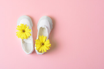 Obraz na płótnie Canvas White ballet flats with yellow flowers on a pink background with copy space.