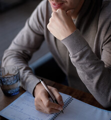 Man works, sits with a pen in his hand and a notebook writes and thinks