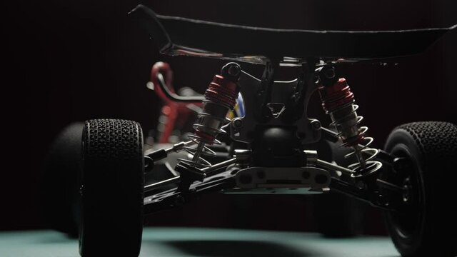 Close-up radio control model buggy car without shell rotating on cutting mat, rear view