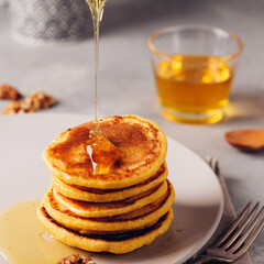 Yellow pancakes with corn flour and turmeric, dressed honey and red grapes. Healthy breakfast with superfoods. Light background, hugge scandinavian style