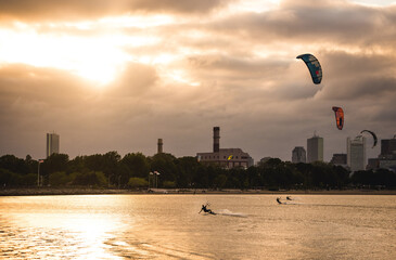 A woman kiteboarding on a summer evening with a cloudy Boston skyline