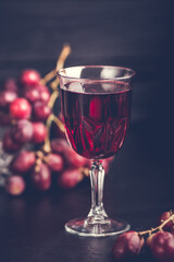 Purple grapes with grape juice in a glass jar, dark picture