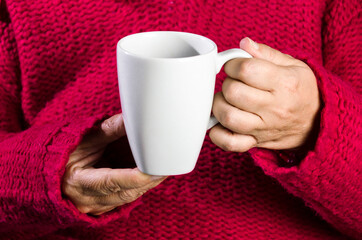 Adult woman with red sweater holding a cup of latte coffee