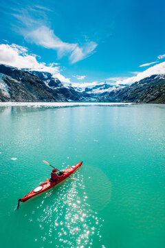 Woman kayaking in Glacier Bay National Park with glacier in background