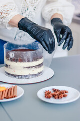 The pastry chef removes the border tape from the naked cake