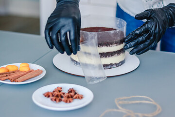 The pastry chef removes the border tape from the naked cake