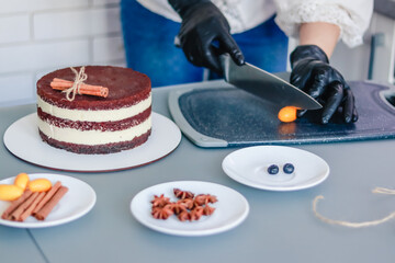 Obraz na płótnie Canvas Pastry chef slices kumquat fruit to decorate the bare cake