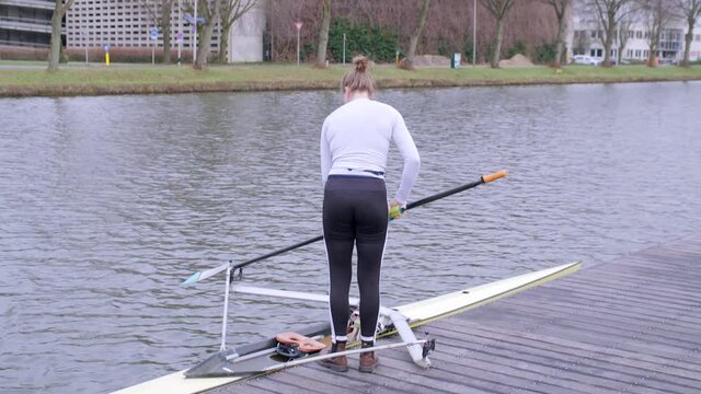 Female rower preparing to go out on Utrecht canal for training in a single scull boat