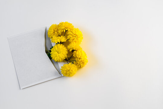 White envelope with yellow chrysanthemums on white background with copy space - Powered by Adobe