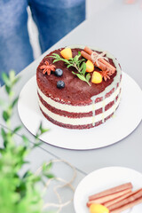 Pastry chef decorates Christmas naked cake with cinnamon sticks, kumquat and thyme sprigs