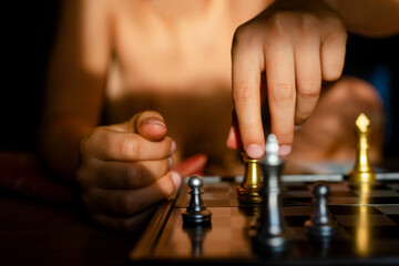 Close-up of a child moving a golden chess piece across a board
