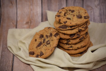 Closeup of a stack of freshly made homemade chocolate chip cookies on a towel with a wood backdrop