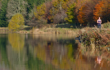 woman running by still lake in south Wales