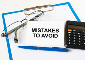 A business card with text Mistakes To Avoid lying on a clipboard with a blue pen eyeglasses and a...
