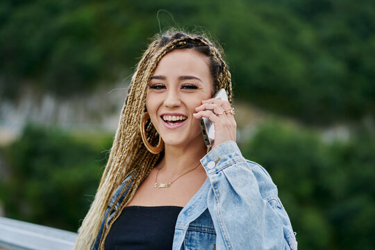 Close-up portrait of a young woman with braided blonde hair talking on her smartphone