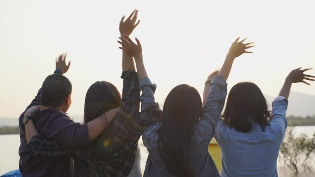 Group of asian teenage friend wave their hands to say goodbye sunset at camping party