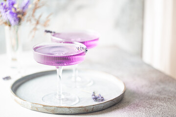 Purple cocktail drink in a glass on white background with flowers