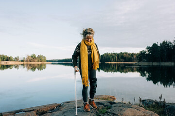injured woman walking on the rocks with crutches in Sweden