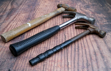 A collection of three hammers on a rustic wooden bench