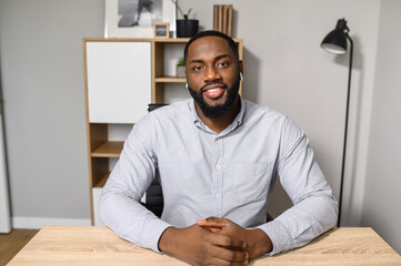 A young and energetic African-American freelancer is ready for an online interview on a video call,...