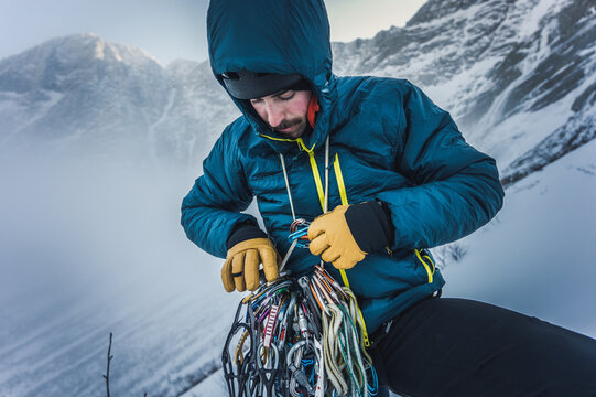 A Man Sorts Through Rock And Ice Climbing Gear During A Winter Climb