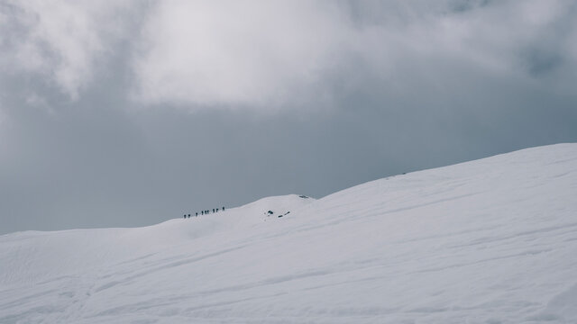 Alpinists trying to summit a snowcapped mountain summit on cloudy day