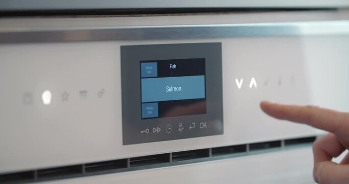 Male finger touching button of modern panel of electric oven.