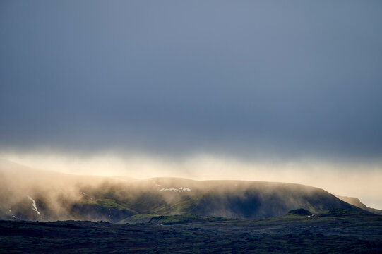 Hilly terrain with dense fog under blue sky