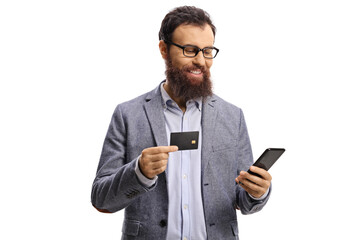 Bearded man with a credit card smiling and looking at a mobile phone