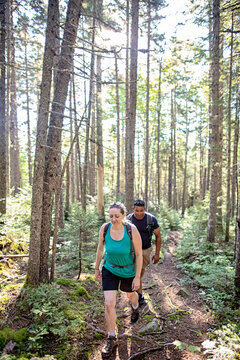 Multi racial couple hike through woods in Maine on Appalachian Trail
