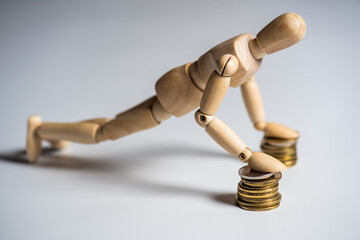 Business Concept . Wooden man and stacked coins isolated on background.