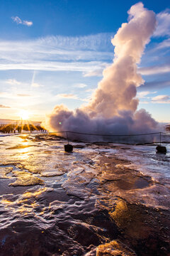 A geothermal geyser erupts in Geysir, Iceland at sunrise