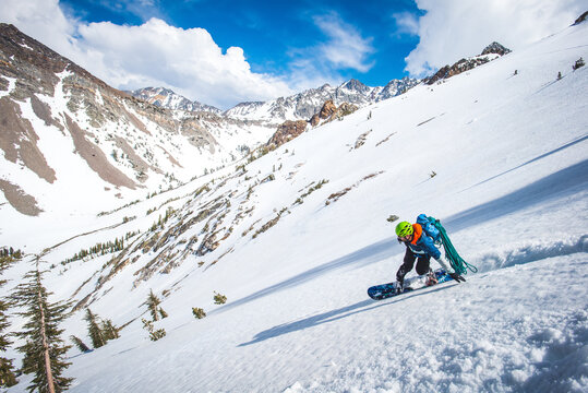Man snowboarding in California backcountry with climbing rope