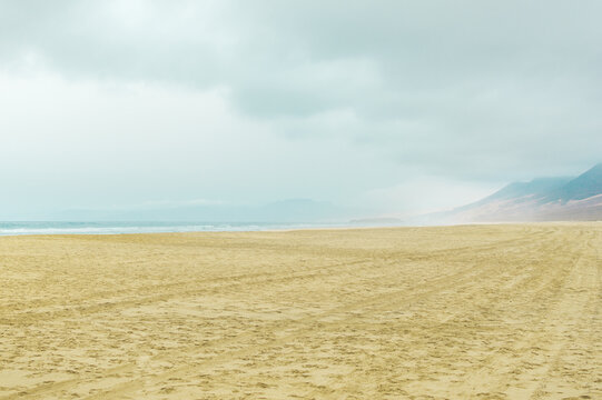 Infinite beach with mountains in the background on hazy and cloudy day. Cofete Beach, Canary Islands.