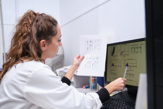 Young female scientist watching at her graphical results in her computer. Laboratory research concept.
