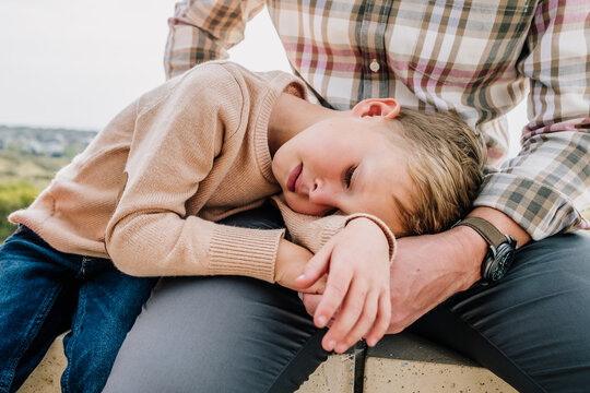 Young boy cuddling father outside