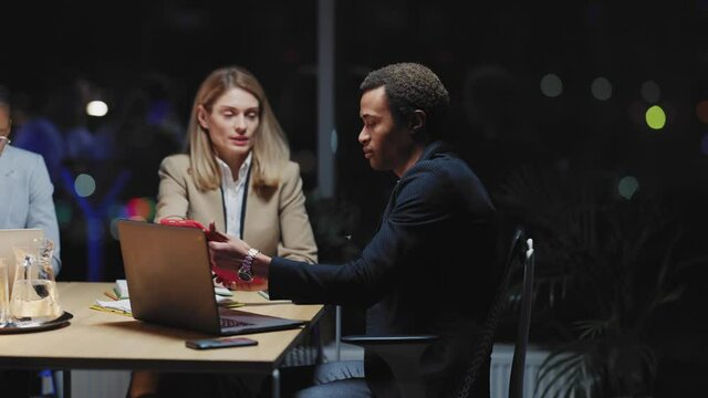 Team of overworked young business people participating in office meeting brainstorming for corporate negotiation. Night office. Working late. Workaholics.