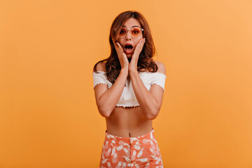 Cheerful girl pouted her lips and poses on orange isolated background. Portrait of naughty model in...